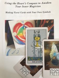 heart's compass with candle aflame in center, ace of cups held in hand, and Draft Book Cover: Using the Heart's Compass to Awaken Your Inner Magician