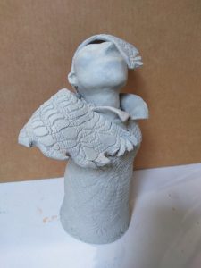 clay angel with one wing over her face