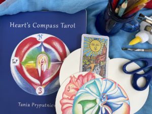 Tarot workbook and three tarot cards with art supplies