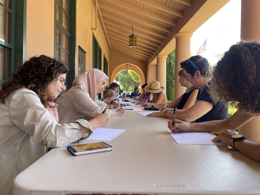 Visions Museum pale tan archways and long table with writers writing